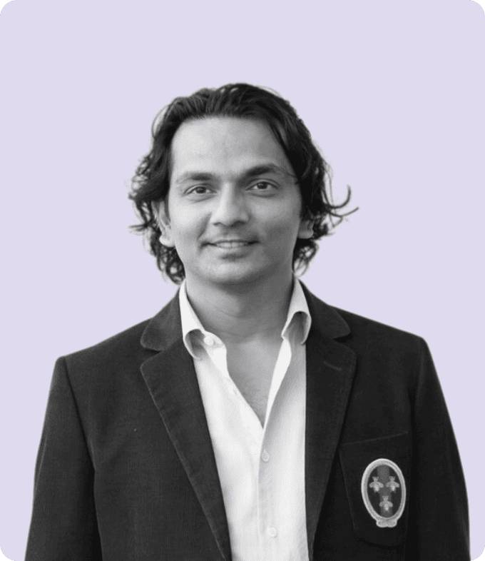 Black-and-white professional portrait of Div Turakhia, Founder of Media.net, smiling slightly, dressed in a formal blazer and white shirt against a subtle lavender background.